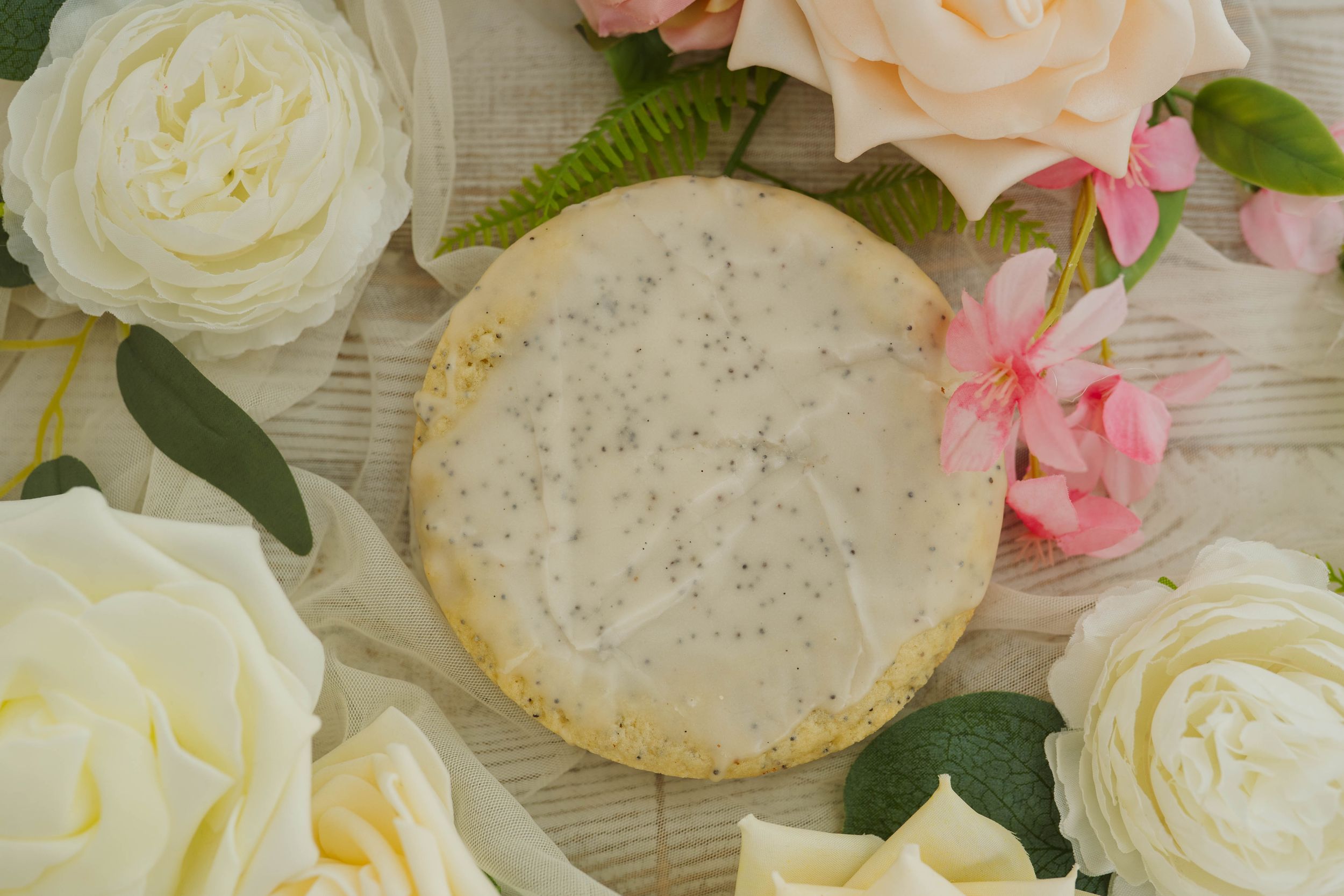 Elegant display of white roses and pink flowers alongside decorated cookies.