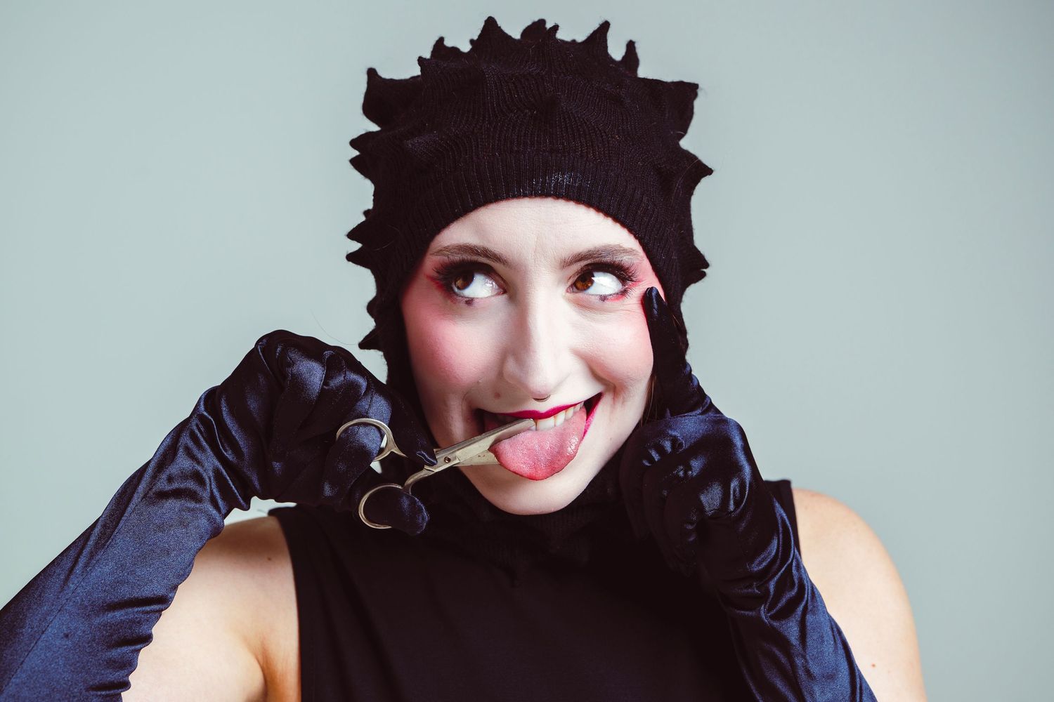 A person wearing a black beanie hat and dark clothing poses playfully in a sequence of four photos.