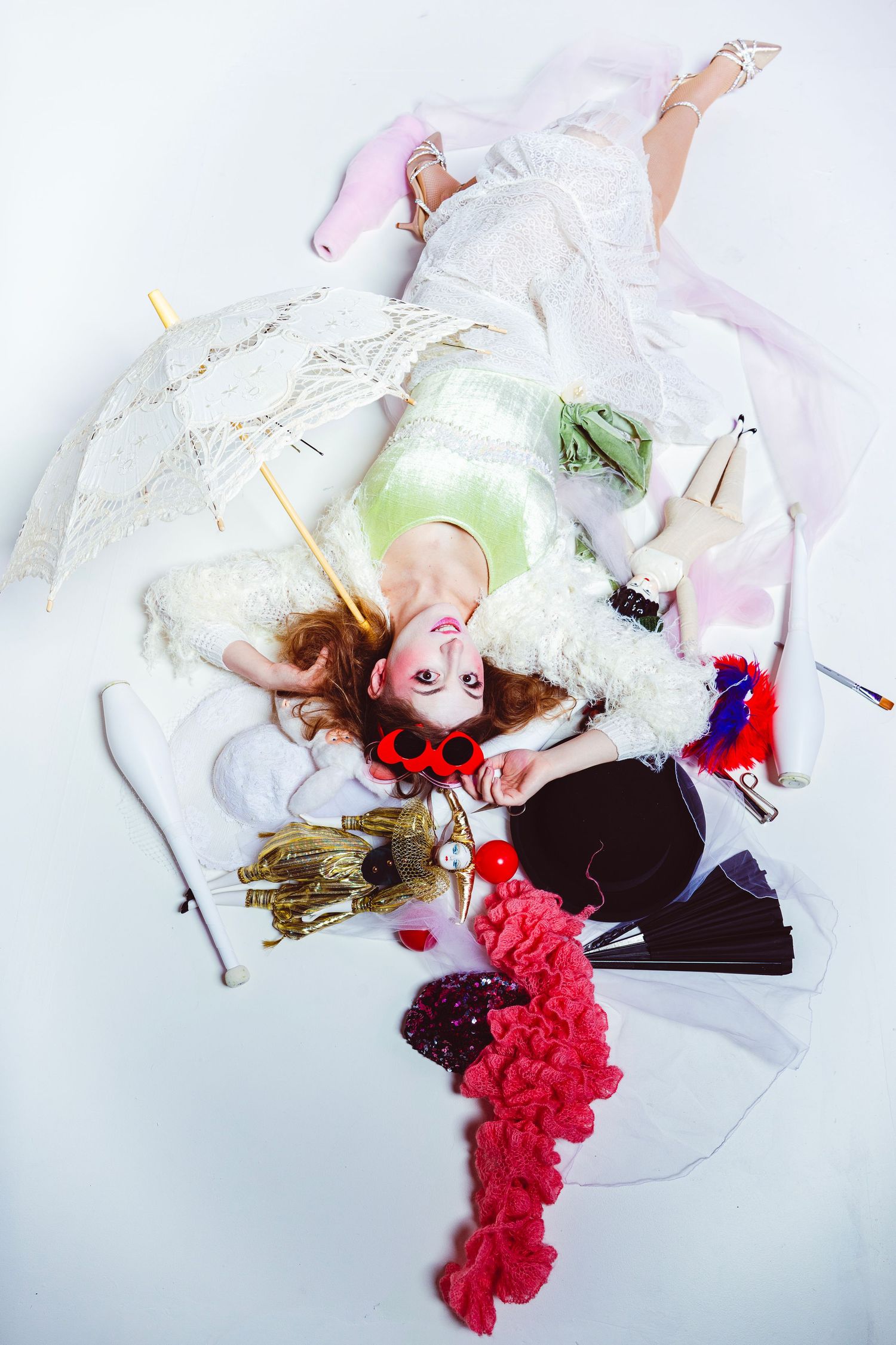 A figure in a white dress lies on a white background with red floral accents in a dreamy artistic composition.