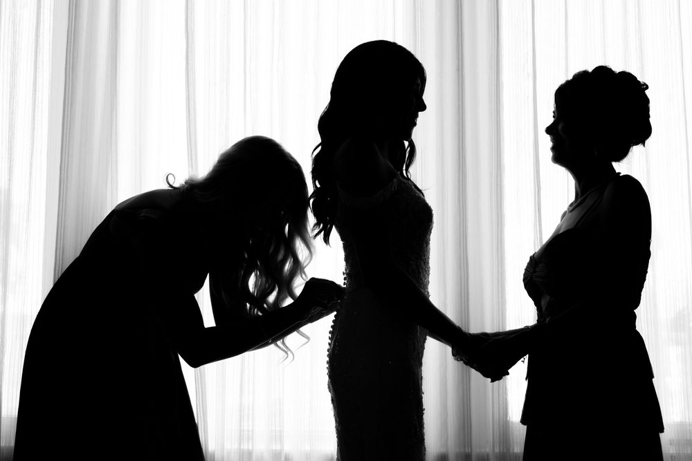 Silhouettes of people standing against a white background form a continuous line of dark figures.