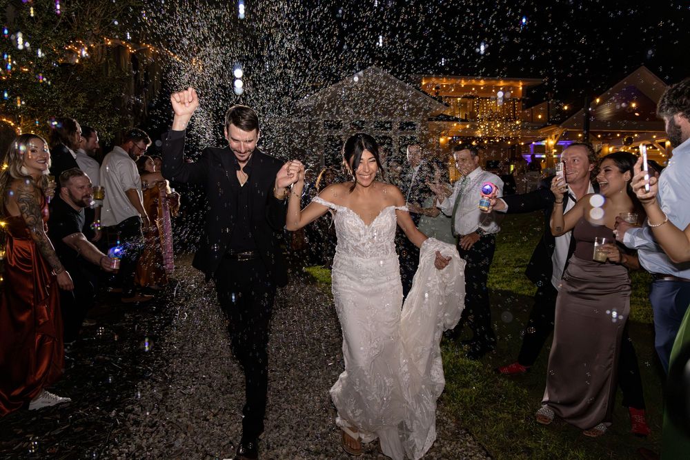 Wedding reception guests dancing and celebrating under twinkling lights at an outdoor evening party.