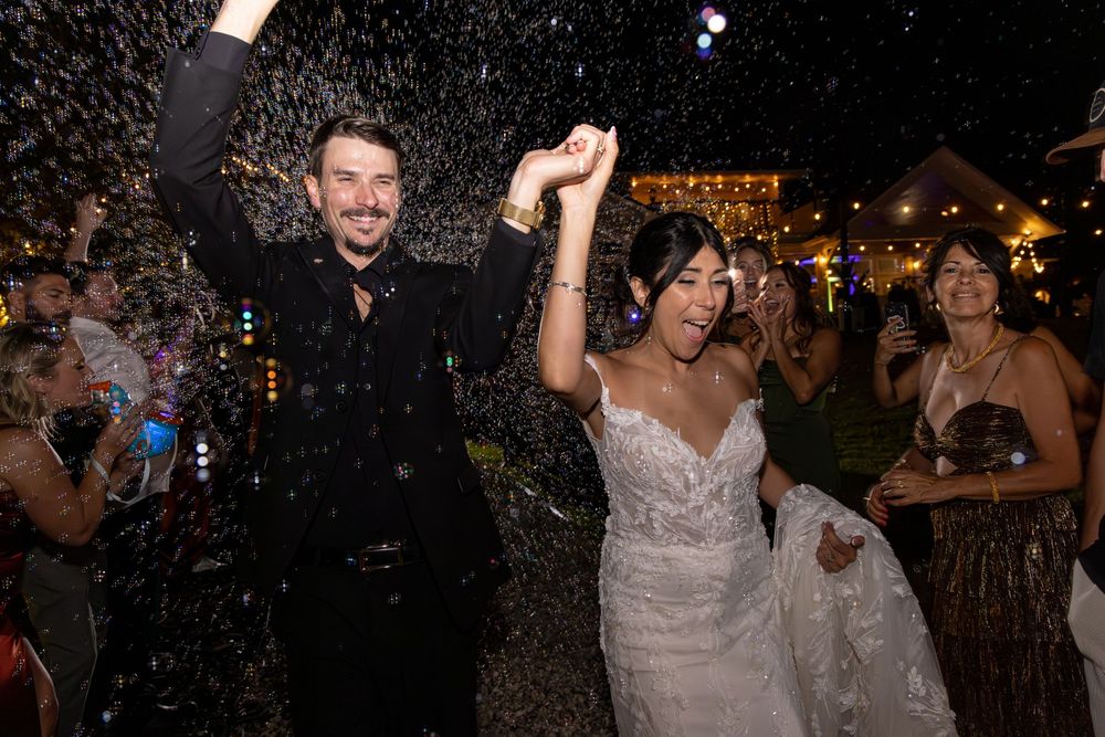Wedding reception guests dancing and celebrating under twinkling lights at night.