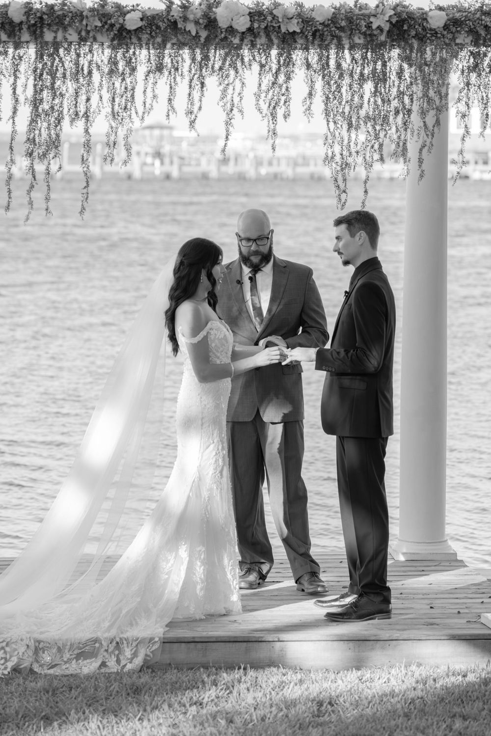 Black and white photo sequence of a wedding ceremony under a gazebo by a lake with four people.
