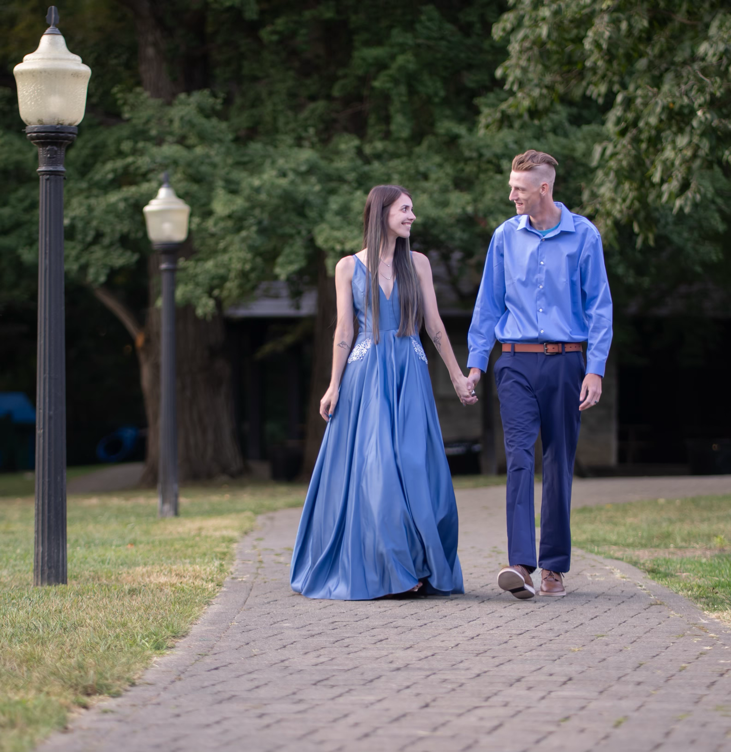 A couple in coordinating blue outfits pose together for an engagement photo