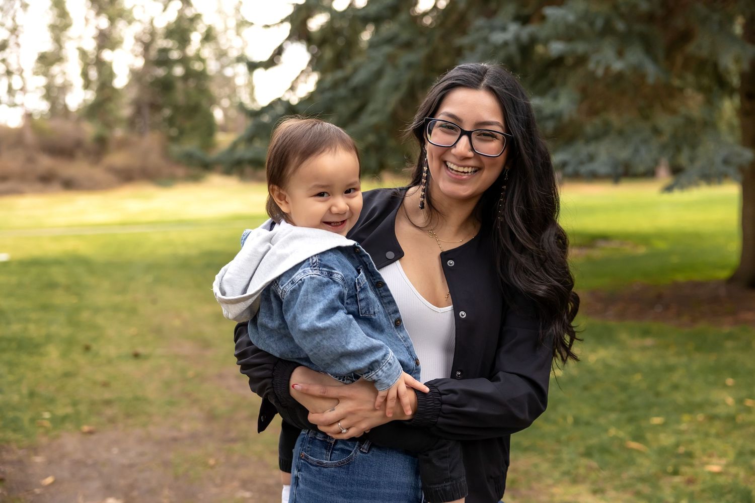 A mother and child share joyful moments together outdoors during a sunny autumn day.