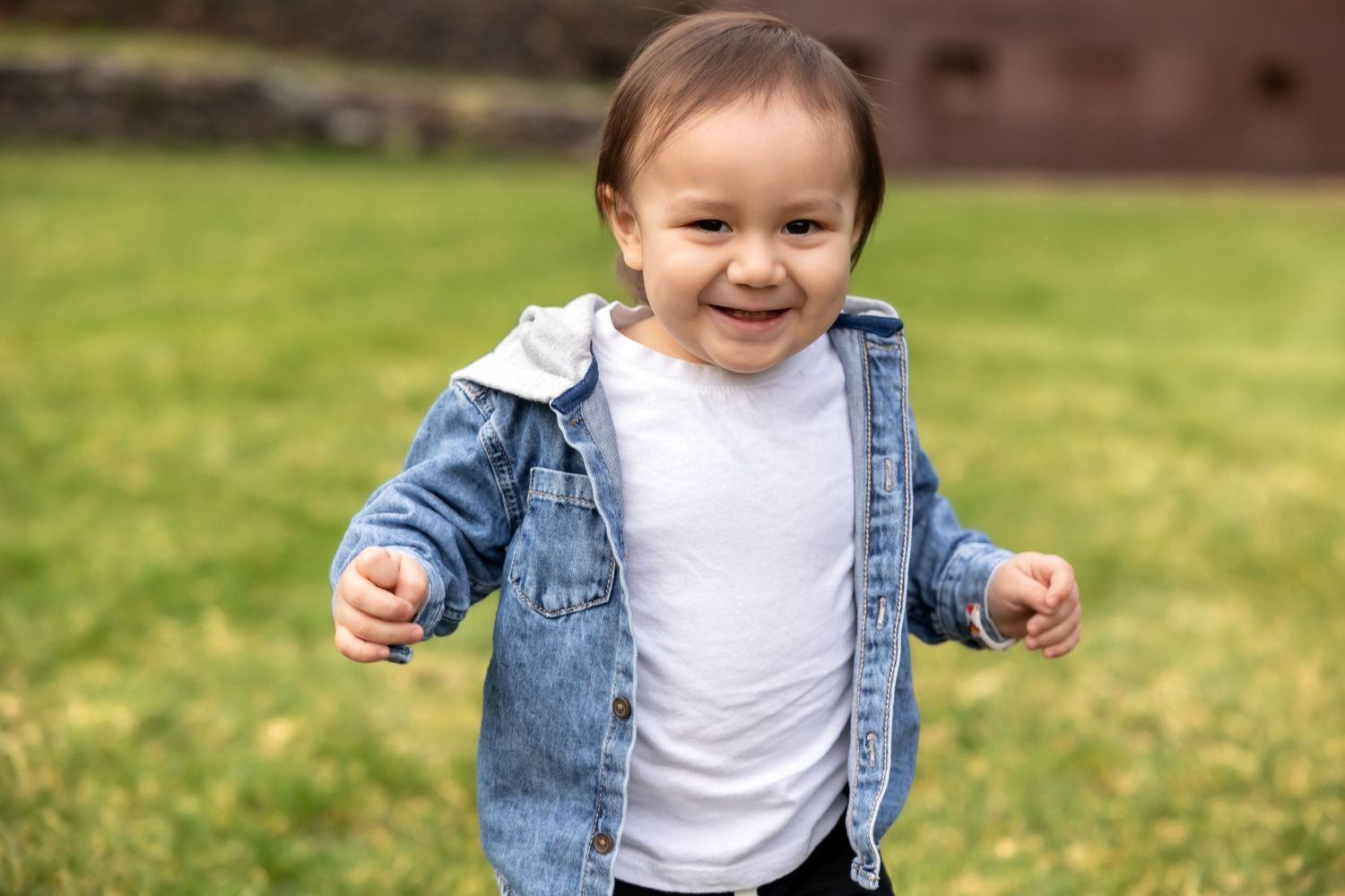 A series of photos showing someone in a denim jacket and white shirt playing and running on green grass outdoors.
