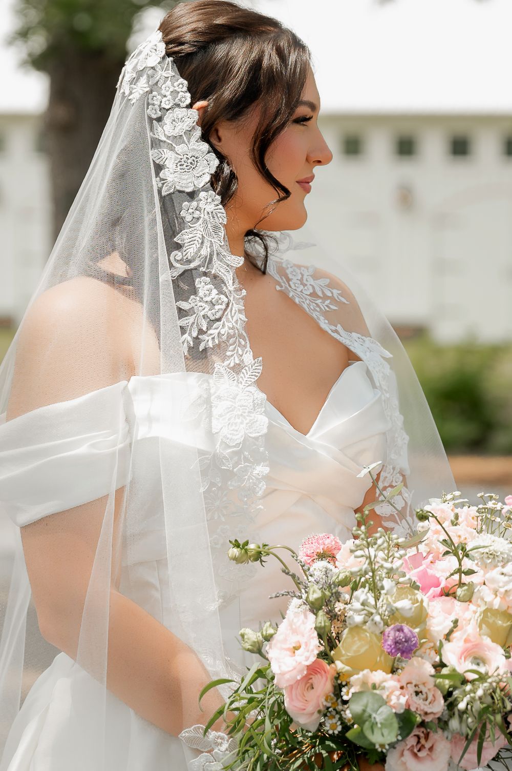 Elegant bridal portrait featuring lace veil and pink floral bouquet.