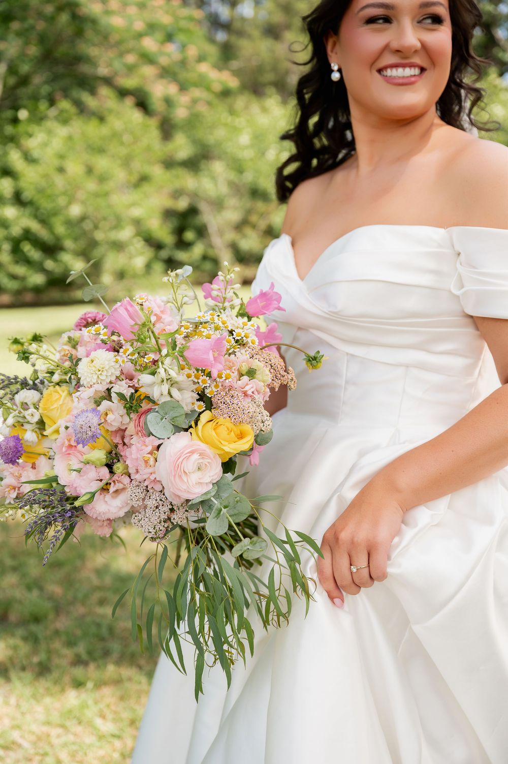 A bridal bouquet features pink, yellow and purple flowers with eucalyptus greenery.