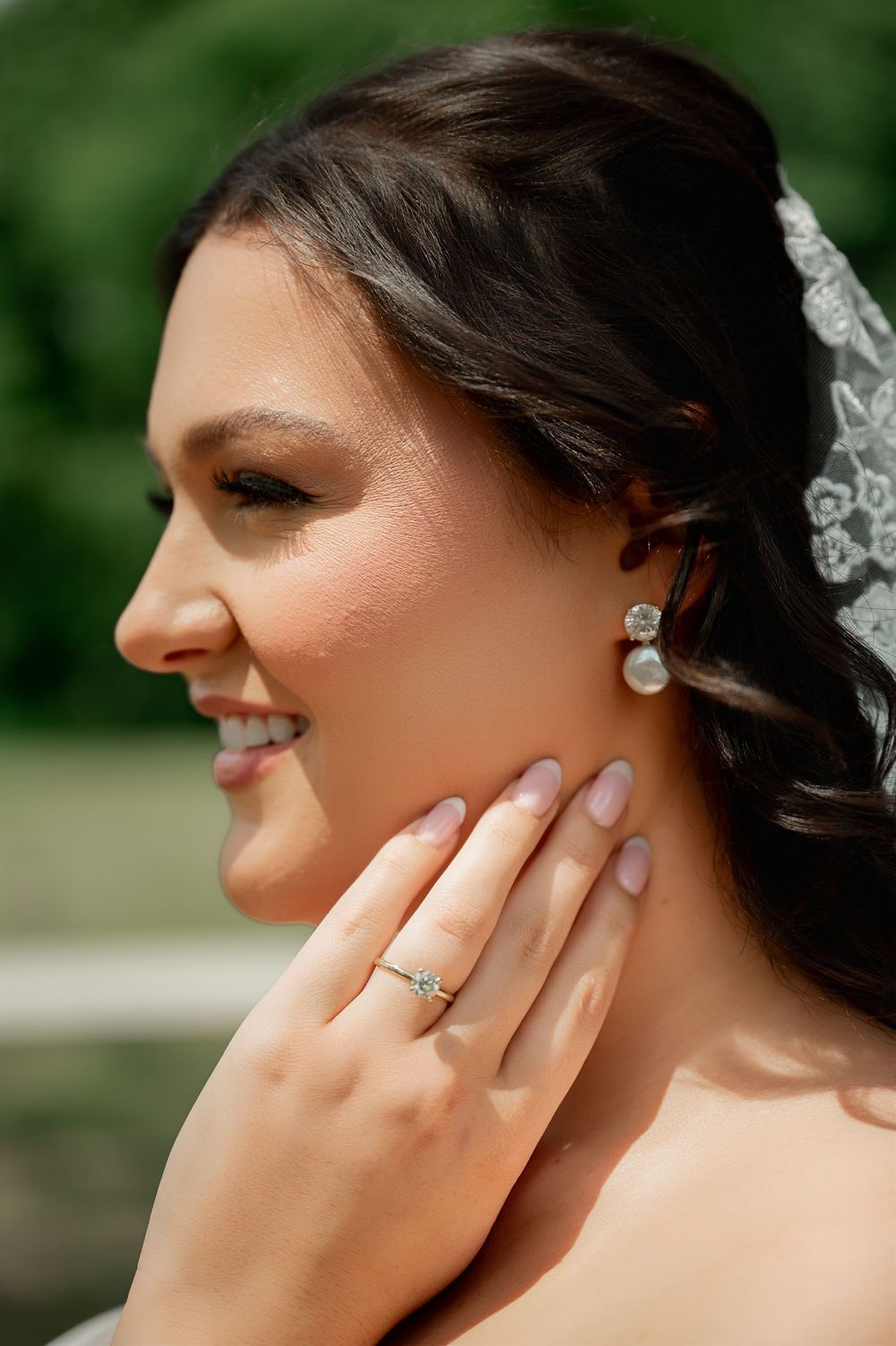 A sparkling engagement ring is showcased on a hand against a soft blurred background.