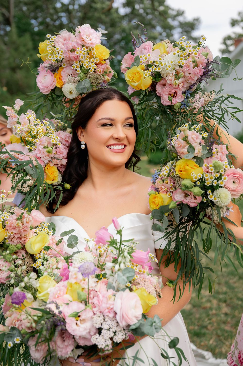 A colorful spring wedding bouquet features pink and yellow blooms with cascading greenery.
