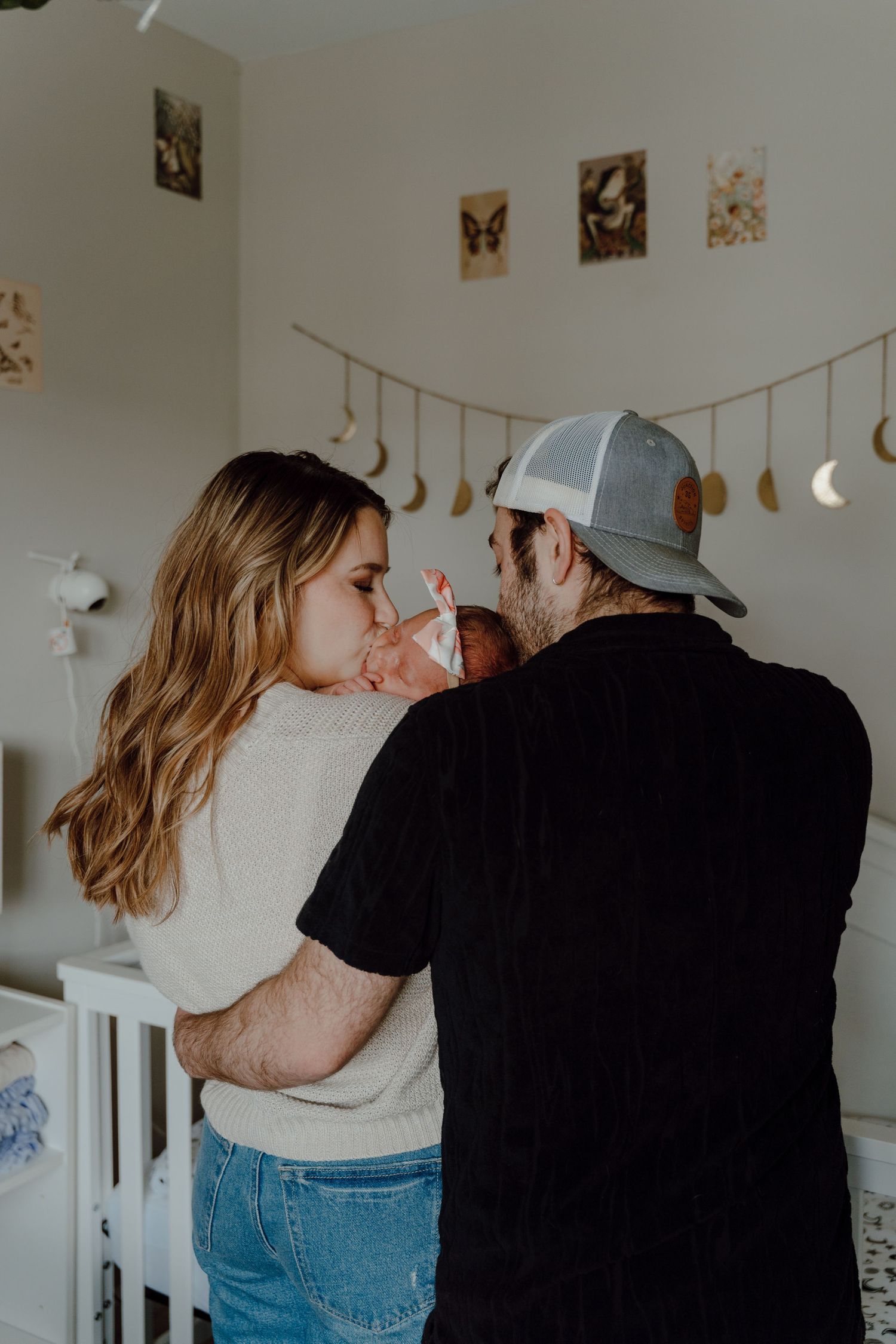 A couple embraces in a cozy indoor setting with photos displayed on the wall behind them.