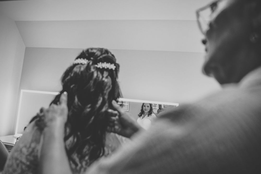 A brides mom helping her clasp her necklace.