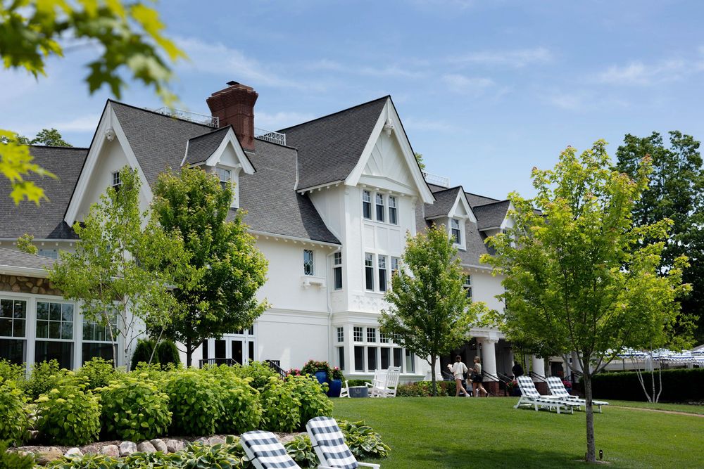 Elegant white Victorian-style hotel The Inn at Stonecliffe with manicured lawn, Adirondack chairs and mature trees on a sunny summer day.
