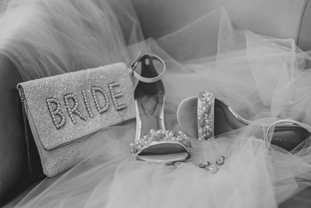 A wedding dress detail shows delicate lace and tulle fabric draped elegantly with soft lighting and bokeh effects.