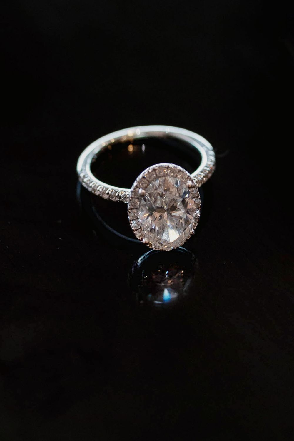 A macro image or a diamond oval cut wedding ring with a reflection.