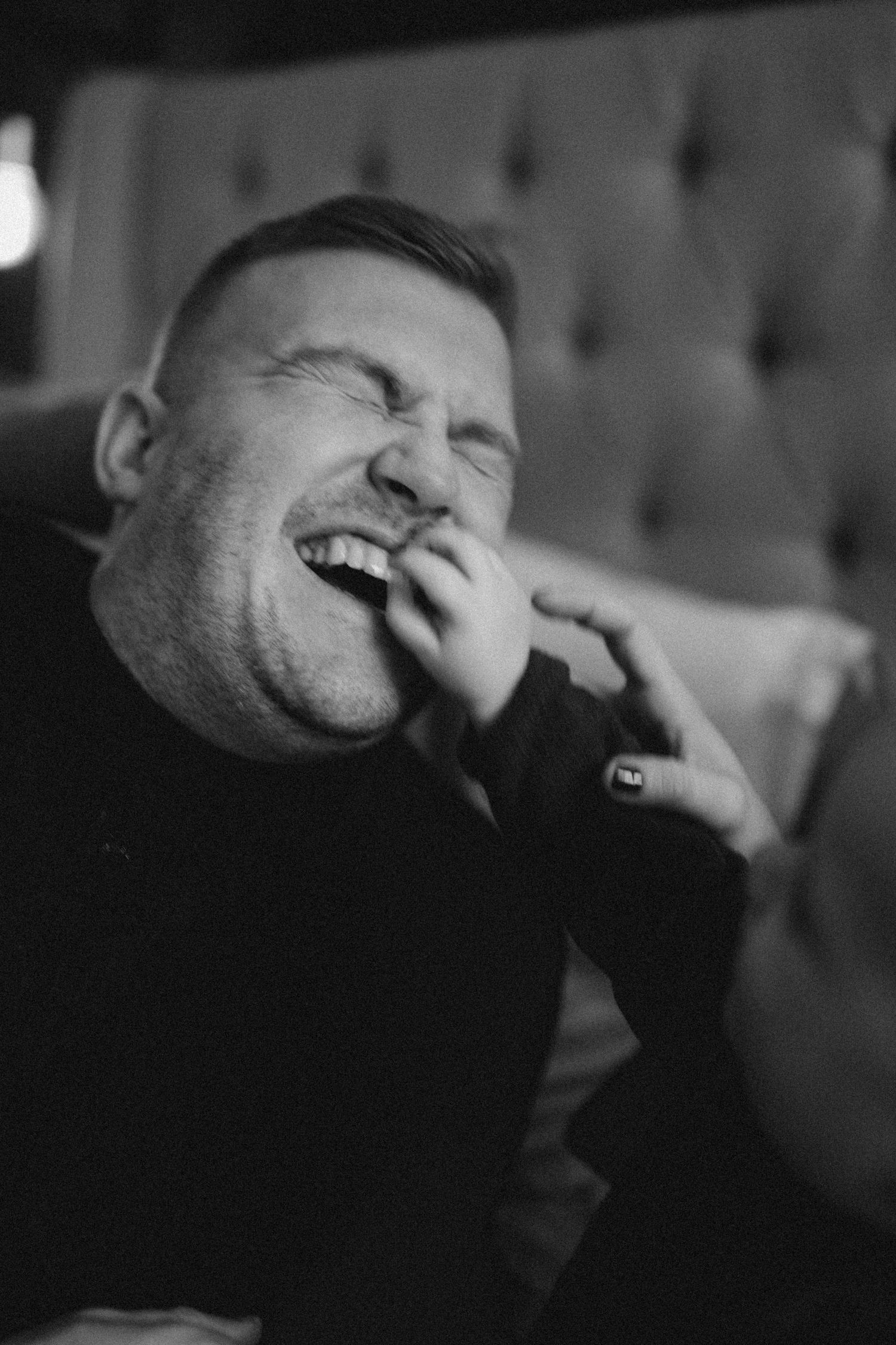 a father is laughing while the hand of his son is in the photo touching his mouth