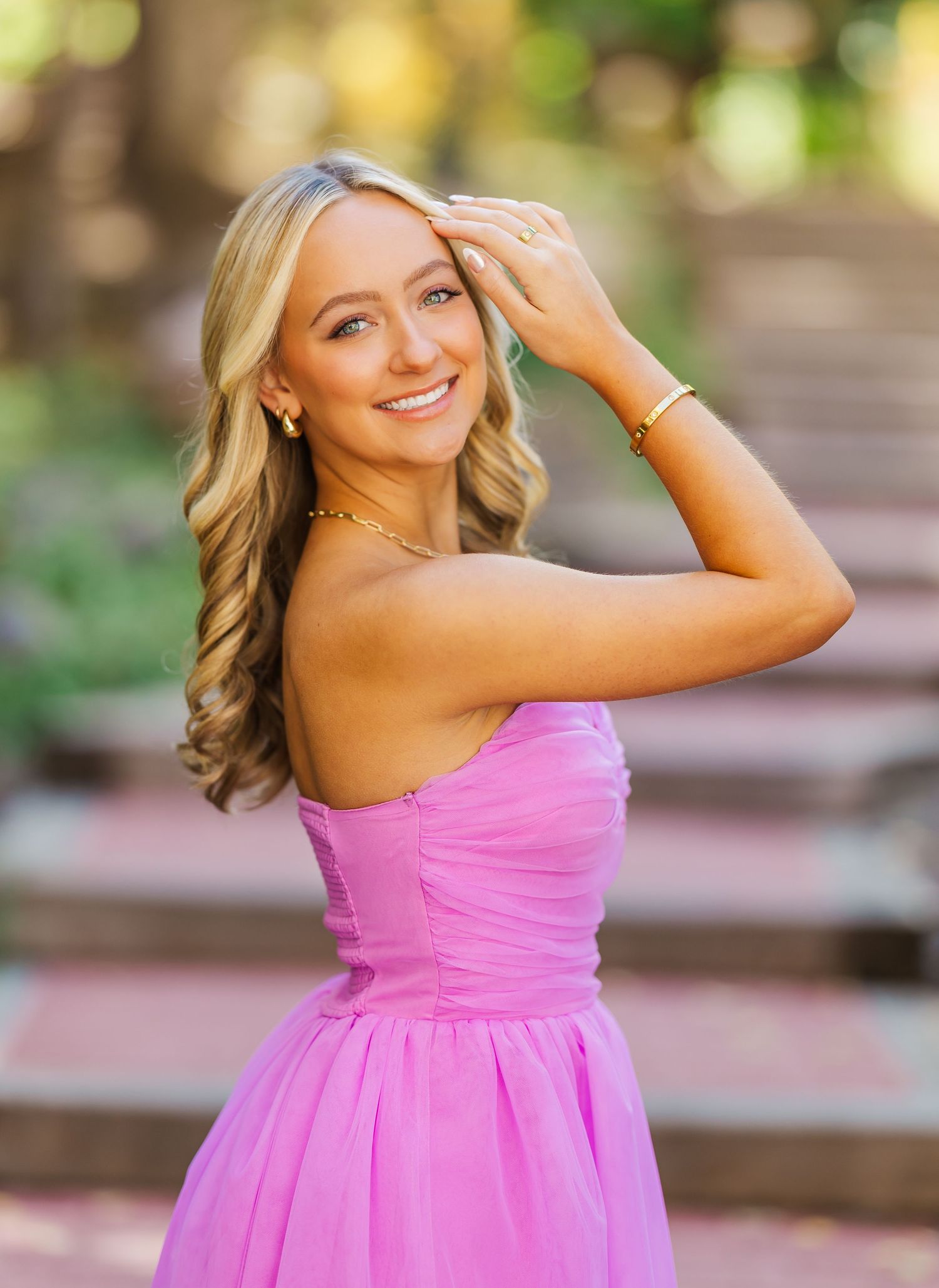 A person wearing a flowing pink dress twirls in front of a blurred outdoor background.