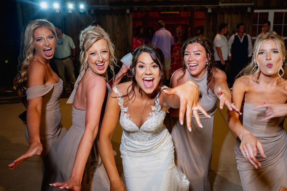 Wedding party members dancing and laughing during an energetic reception celebration.