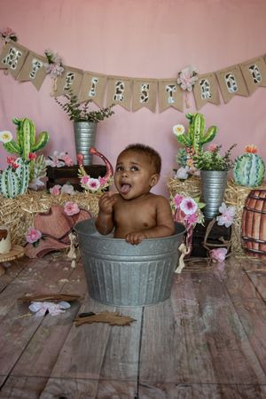Rustic party setup with galvanized tub, cactus decorations and pink flowers against wooden backdrop.