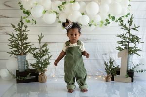 White balloons and evergreen branches create an elegant winter party decoration against a white shiplap wall.