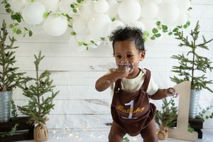 Series of candid moments during a cake smash photo shoot with rustic wood slice cake stand.