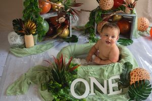 Tropical themed first birthday party decorations with palm leaves, pineapples, and peach-colored accents.