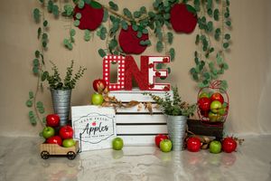 Red roses and green vines create a romantic backdrop with rustic decor and apples on display.