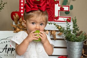 Festive holiday setup with red bows, green eucalyptus, and apples on a white surface.