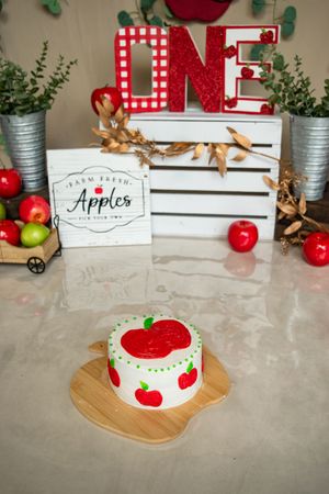A series of five decorative apple-themed vignettes with red and white farmhouse decor on a marble countertop.