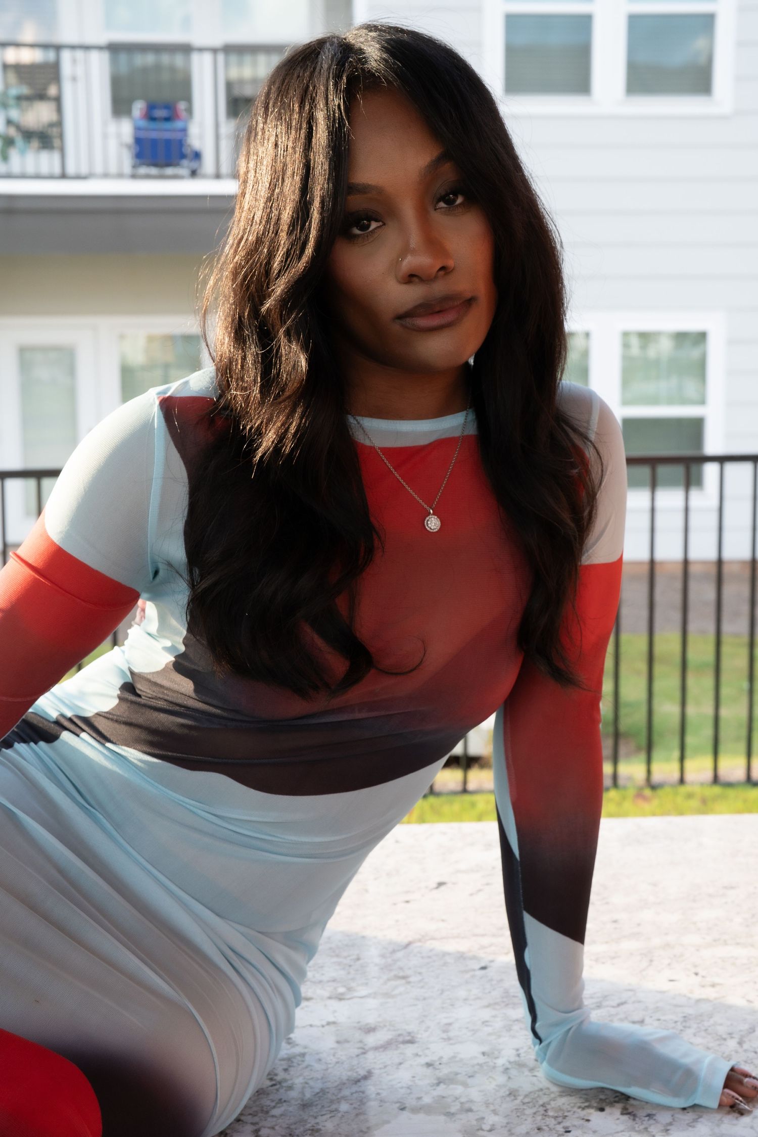 A model in a red long sleeve top and white dress poses for a series of fashion photos.
