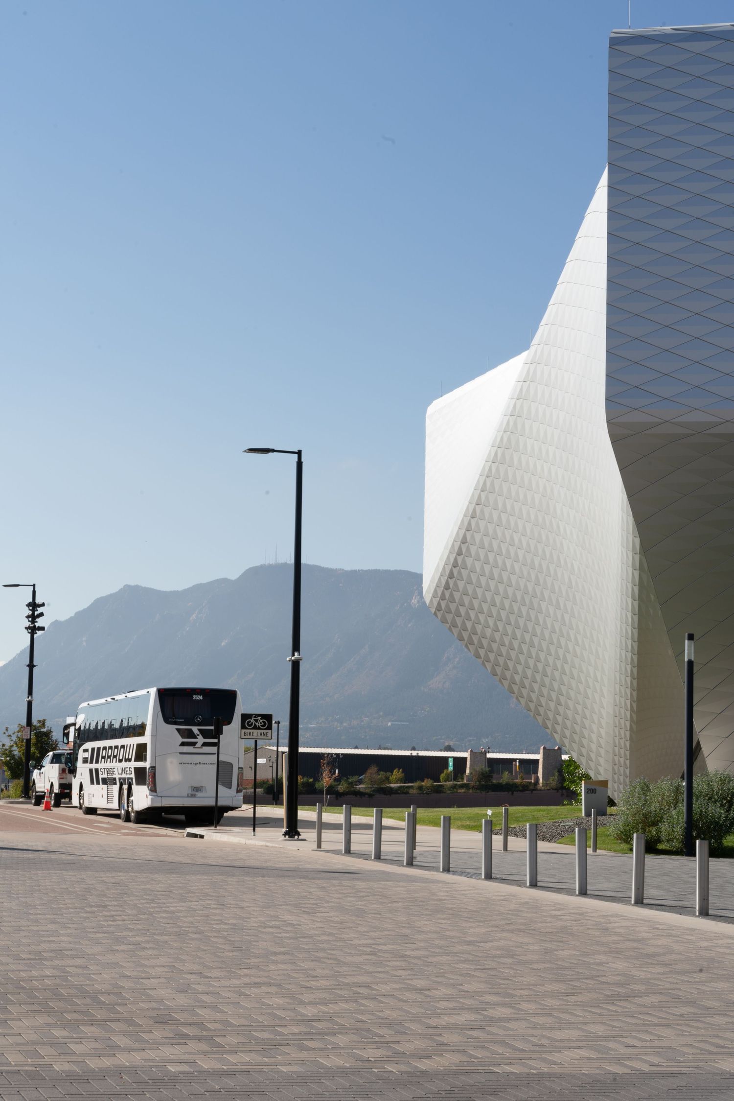 Modern white architectural structure against blue sky with mountains in background.