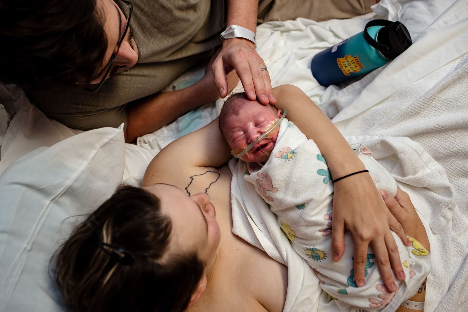 Raw emotional moment between mom, dad, and newborn after birth before a hospital transfer