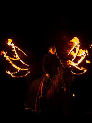 Un cavalier à cheval, entouré d'ailes enflammées, offre un spectacle nocturne saisissant.