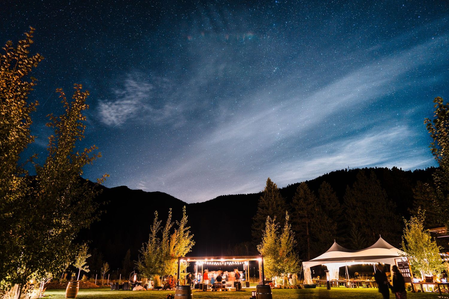 Outdoor evening wedding reception under a starry night sky with mountain backdrop and illuminated white tents. north cascades elopement wedd