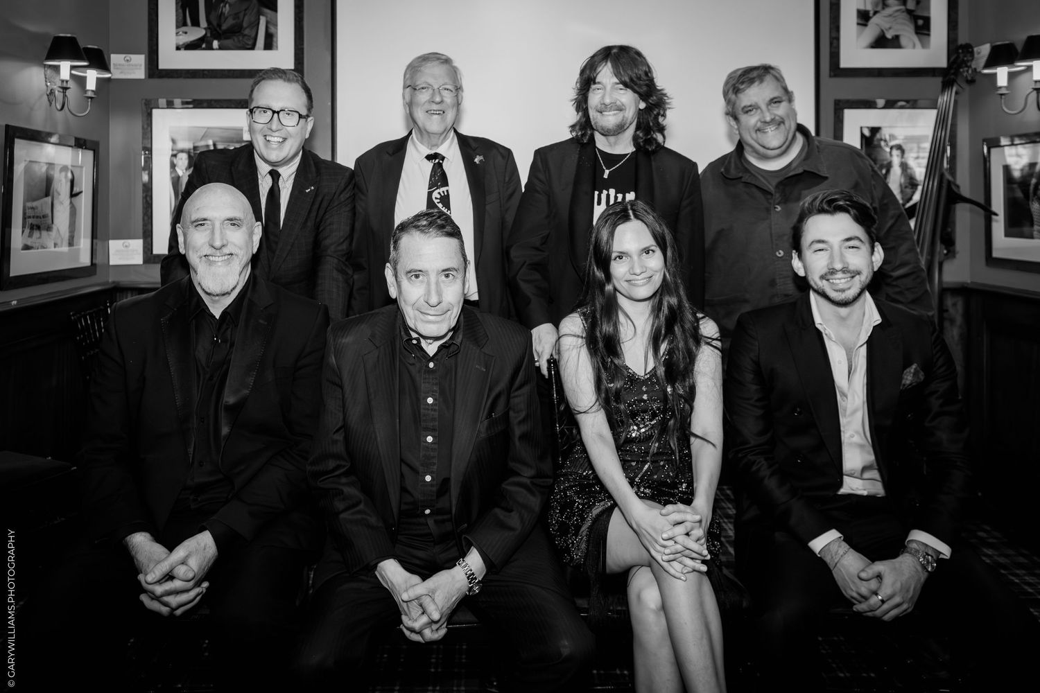 A group of people pose together for a photo in a room with red walls and dark wood paneling.