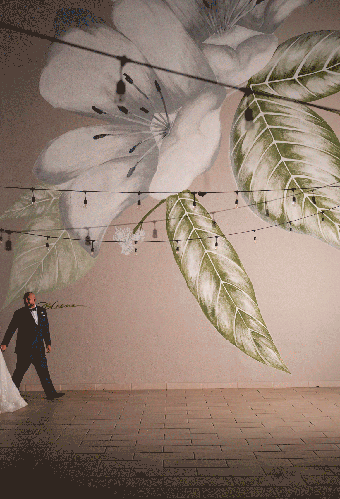 Couple posing in an artistic indoor setting with soft lighting and large botanical wall design at marriott Stelaris