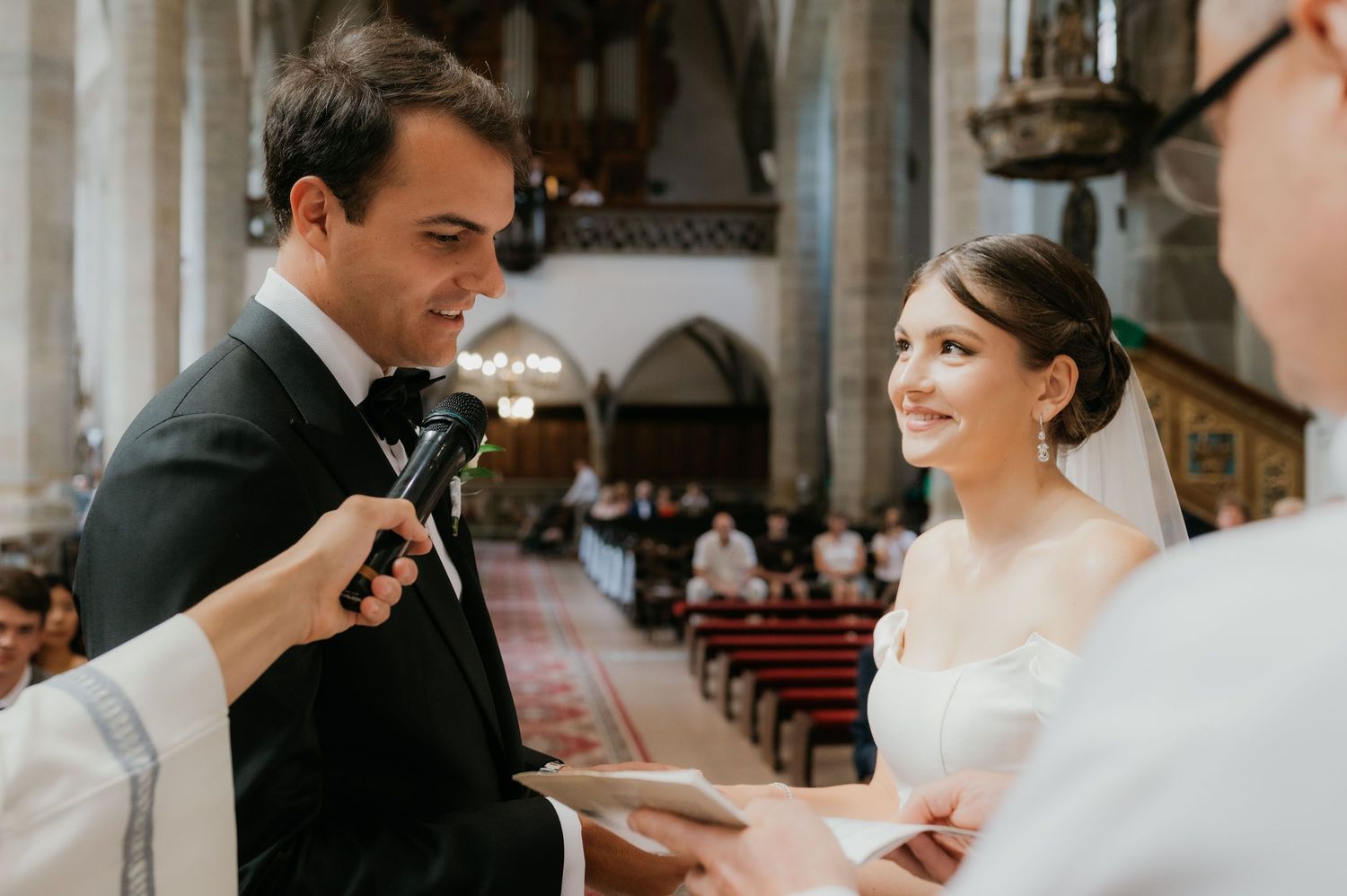 Groom reads vows to smiling bride at elegant church wedding ceremony.