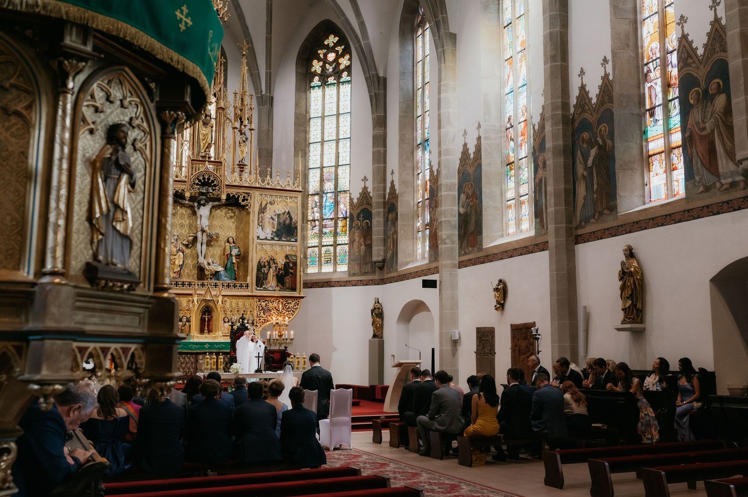 Guests seated in an ornate Gothic church during a beautiful wedding ceremony.