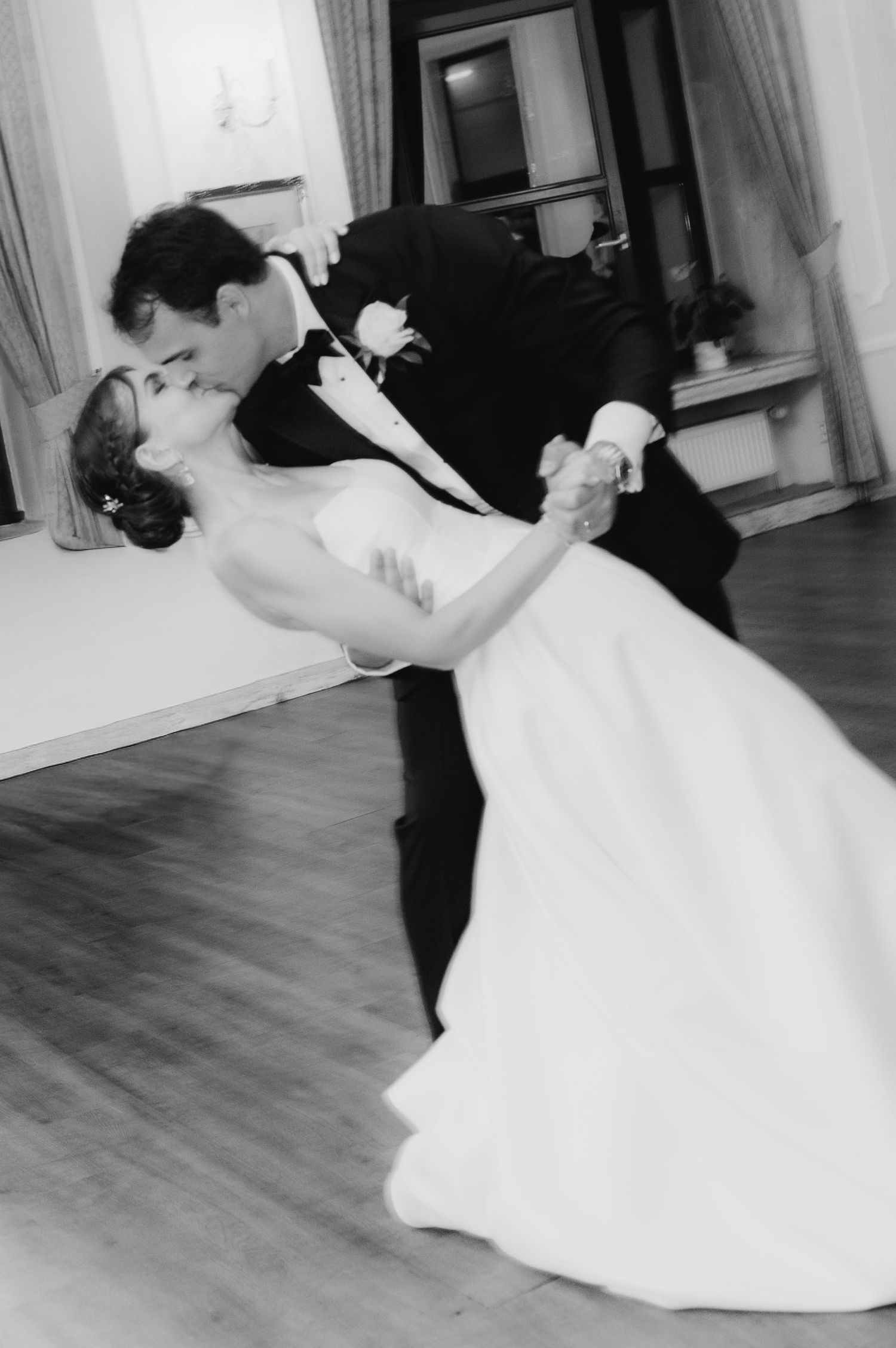 Black and white photo of a bride and groom sharing a romantic dip kiss during their first wedding dance.