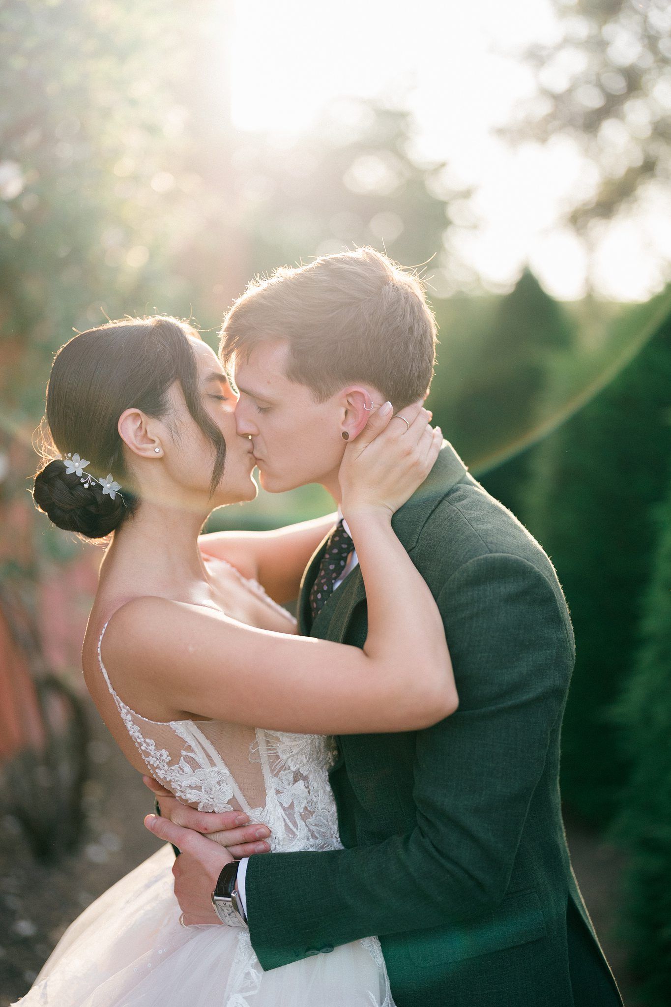 Black and white photo of a bride and groom sharing a romantic kiss outdoors on their wedding day.