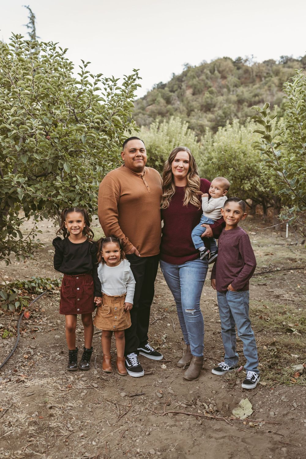 Family of six posing outdoors in an apple orchard in oak glen ca with heidi grace photography