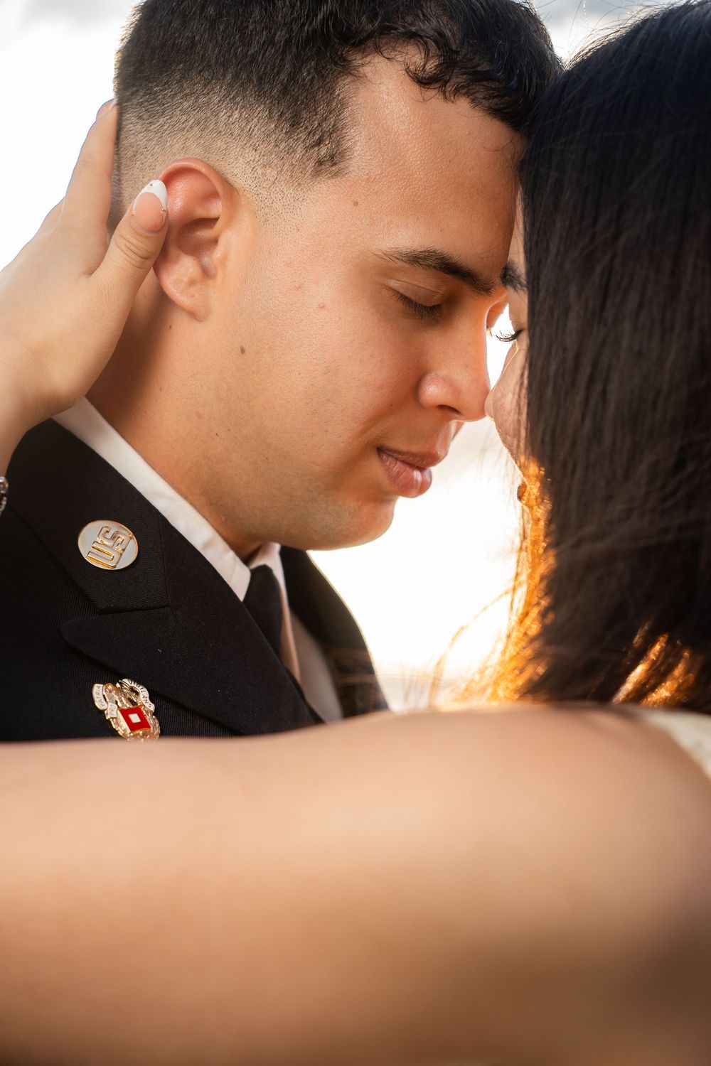 A soldier in uniform shares a tender moment with a woman, their foreheads touching in a romantic embrace.