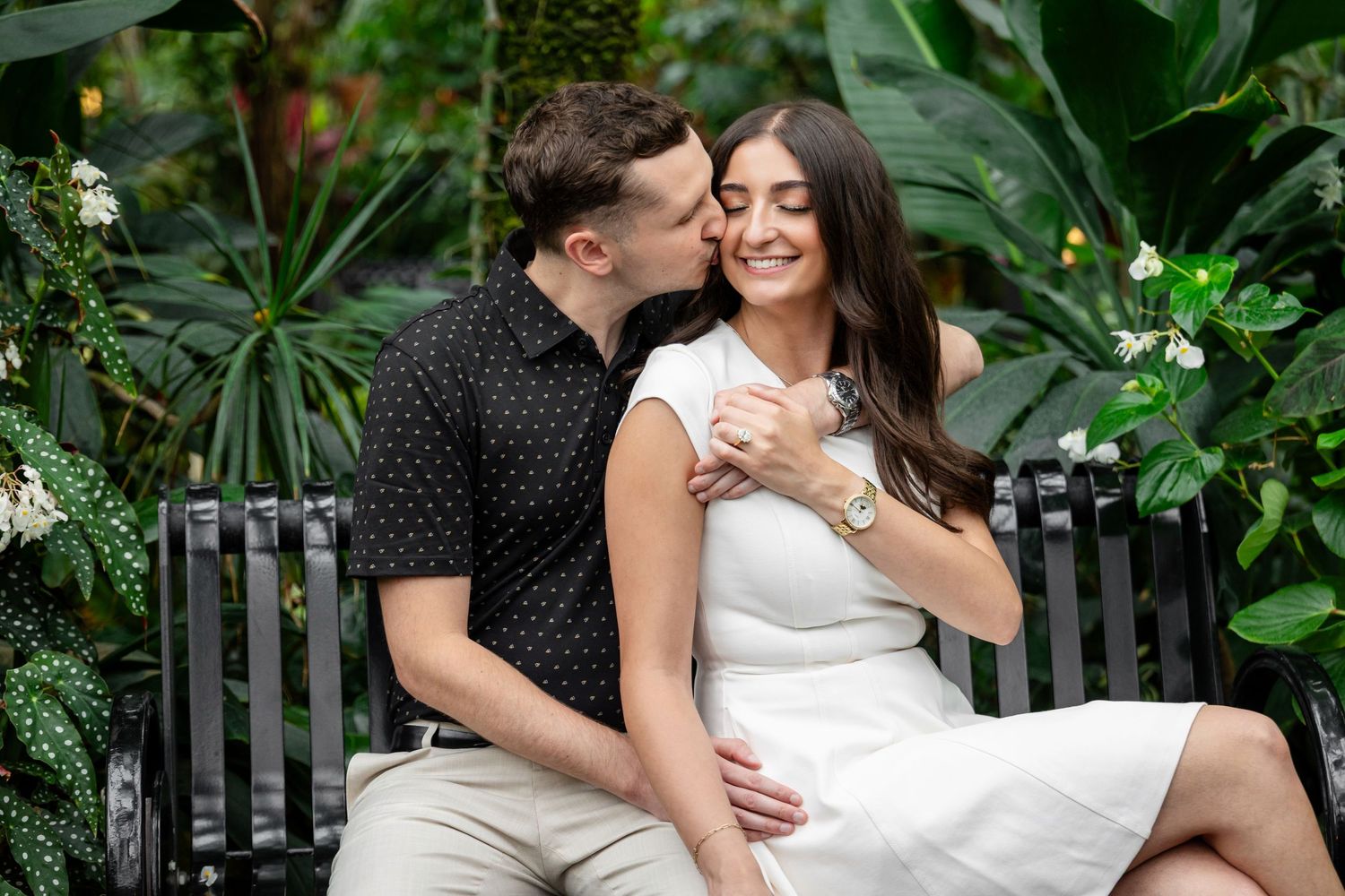 A couple in wedding attire shares romantic moments in a lush tropical garden setting.