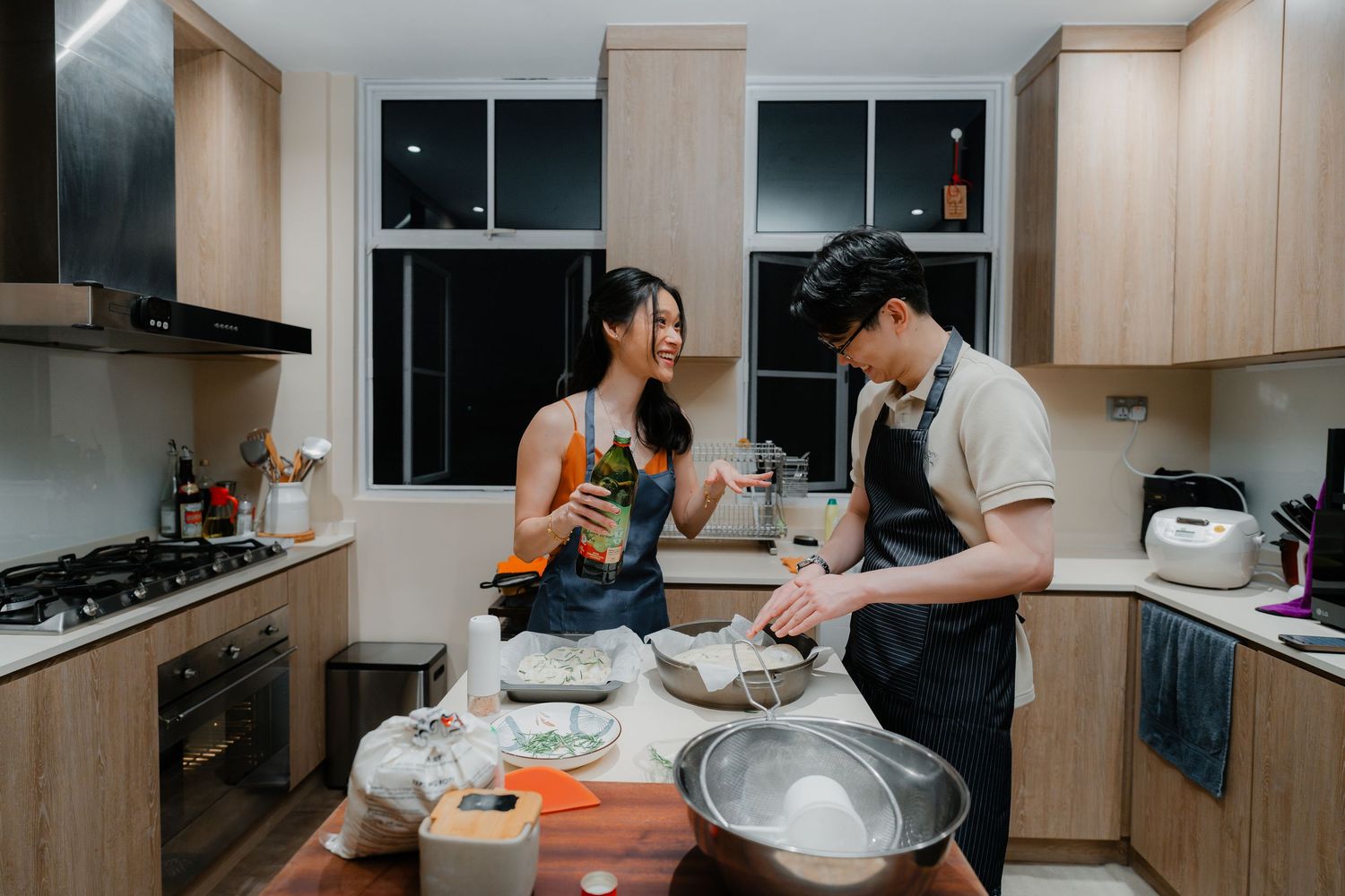 Two people cooking together in a modern kitchen with wooden cabinets.