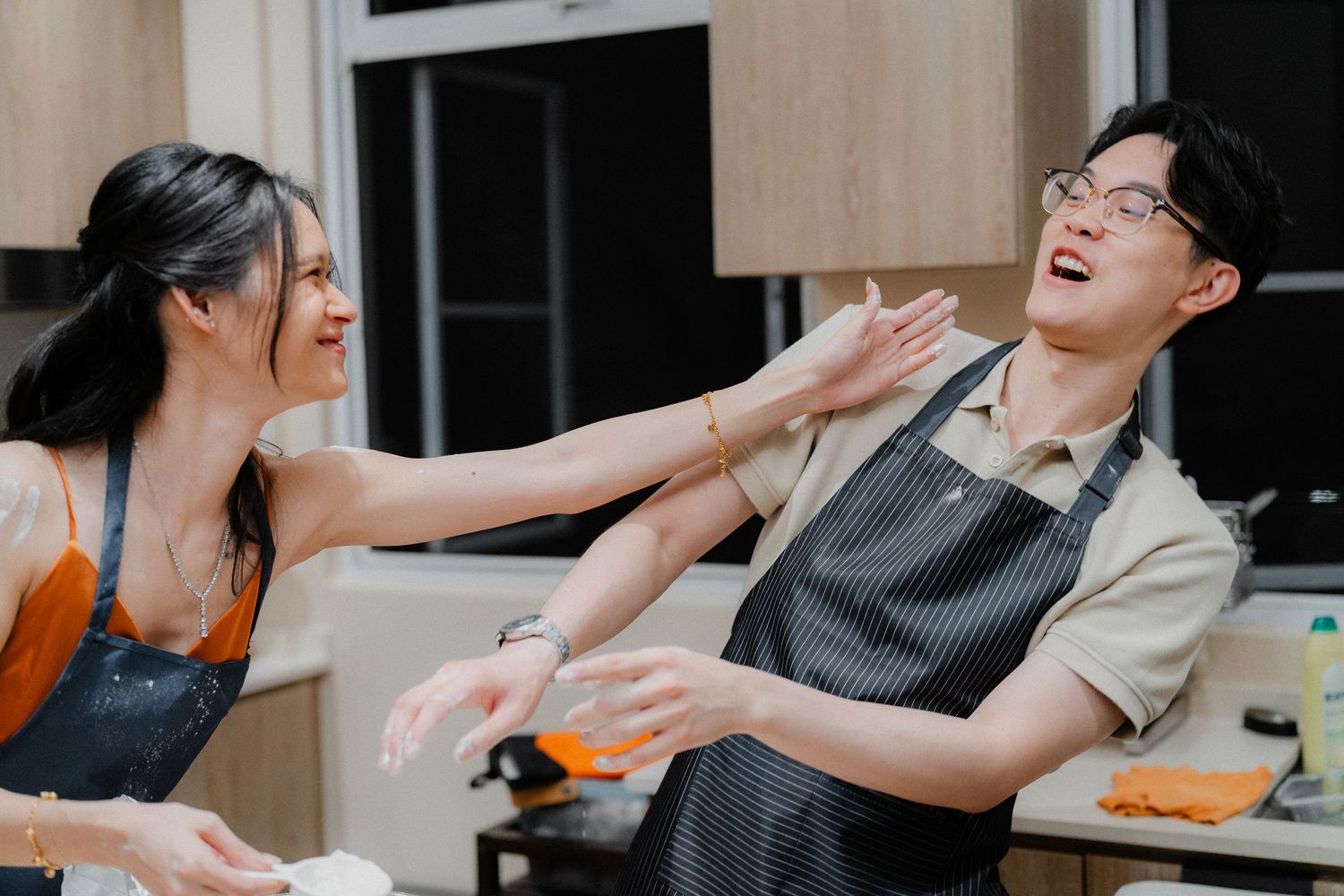 Couple laughing and playing while preparing food in their kitchen.