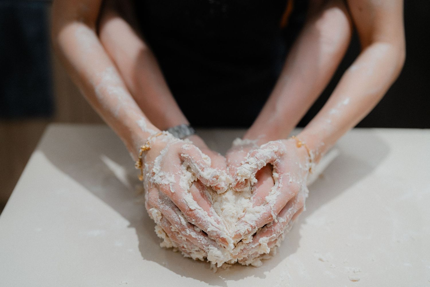 Close-up shot of hands covered in flour while kneading dough.
