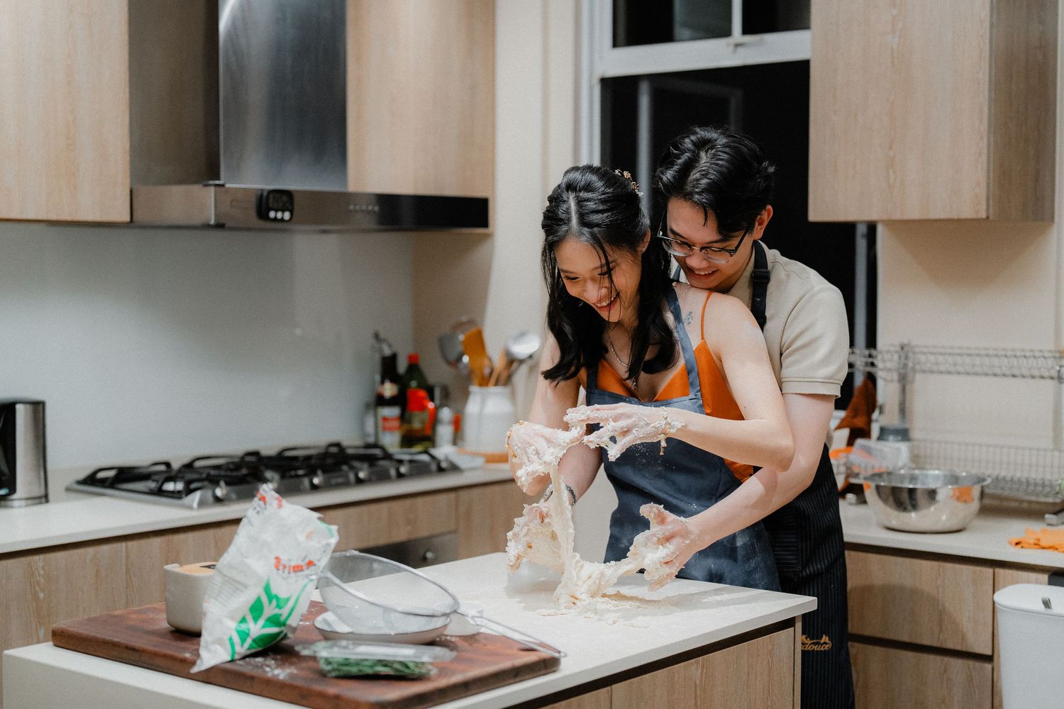 Two people working together to mix ingredients in a modern kitchen with wooden cabinets.
