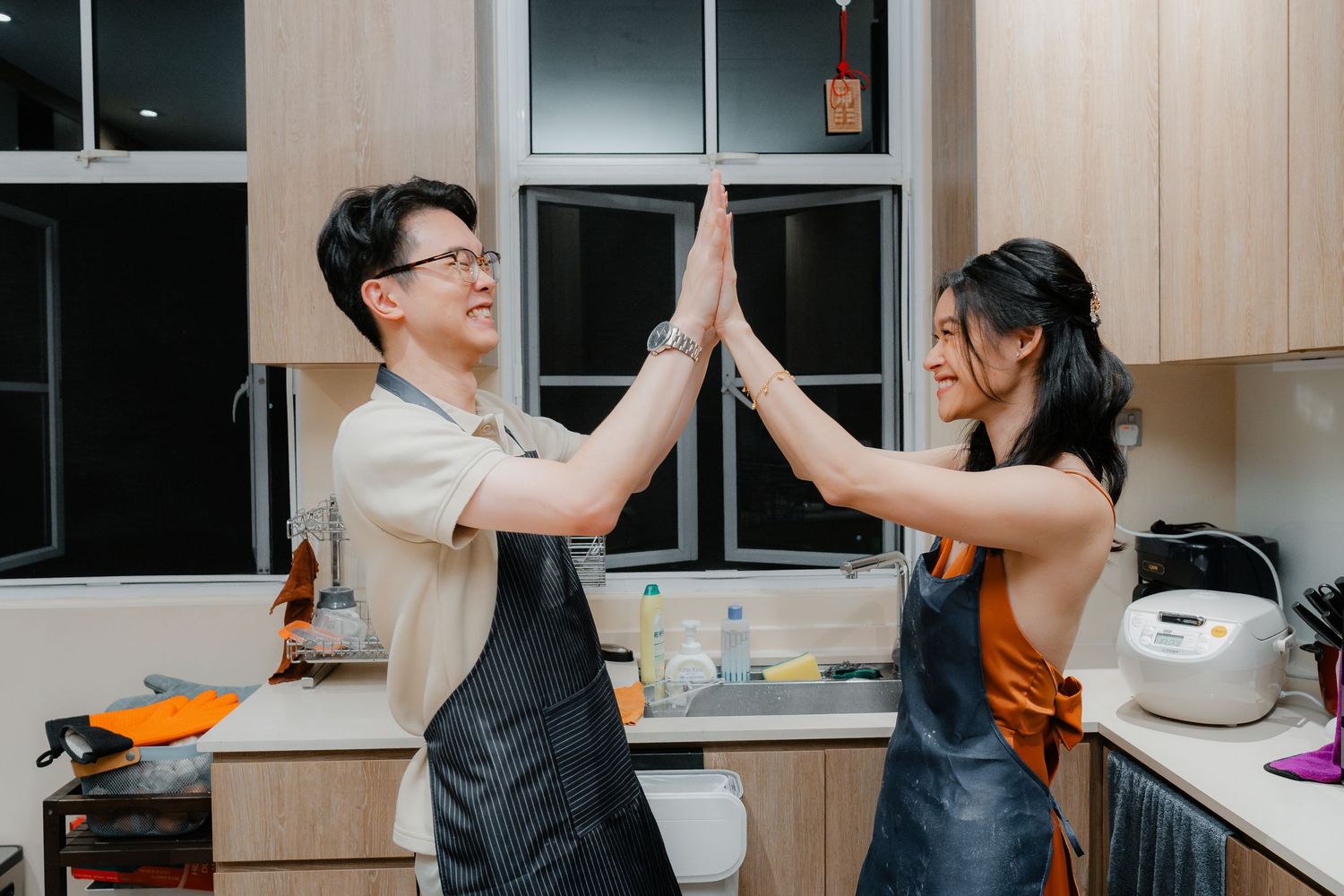 Two people giving high five while cooking together in modern kitchen setting.