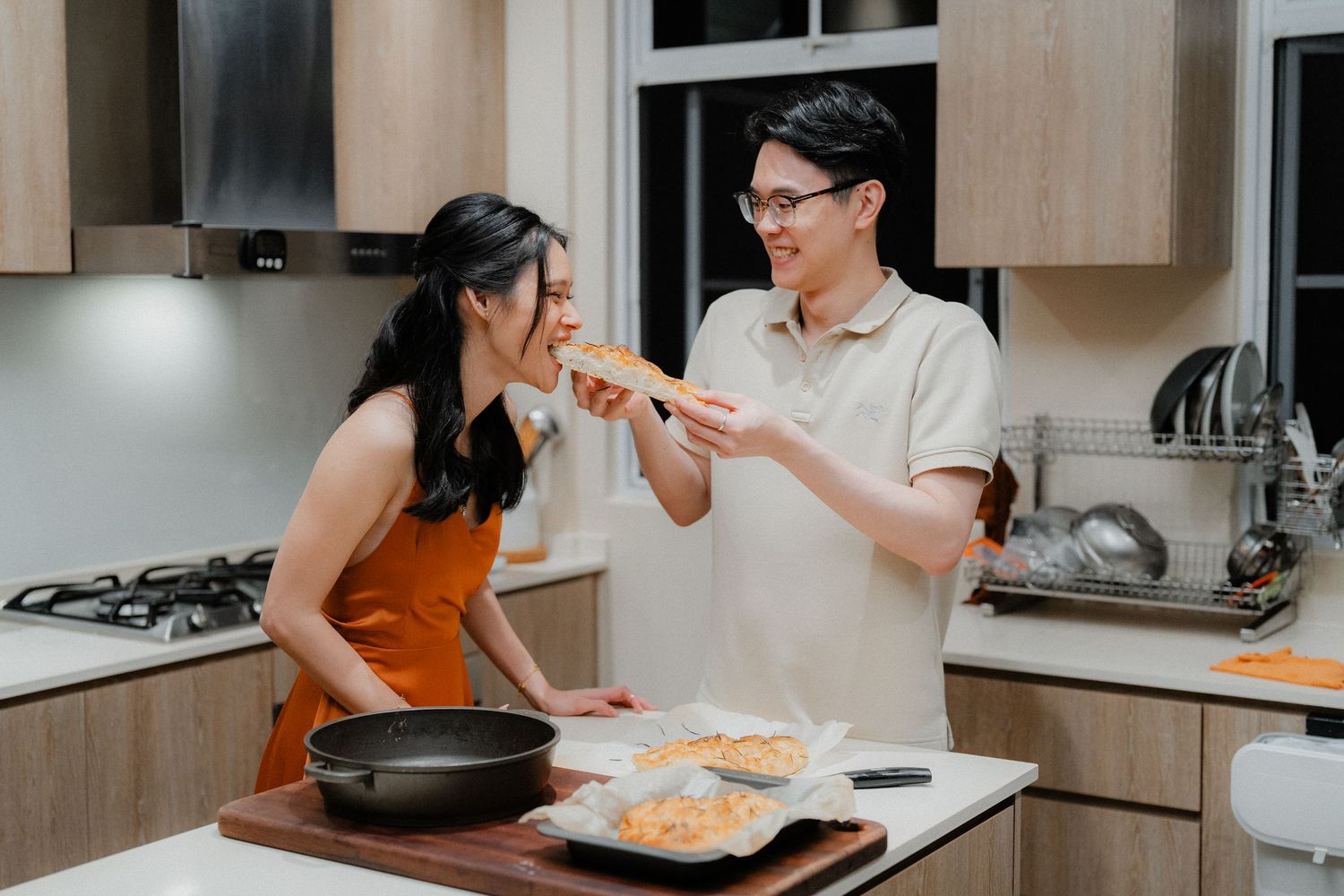 Two people sharing a taste test moment while cooking in their kitchen.