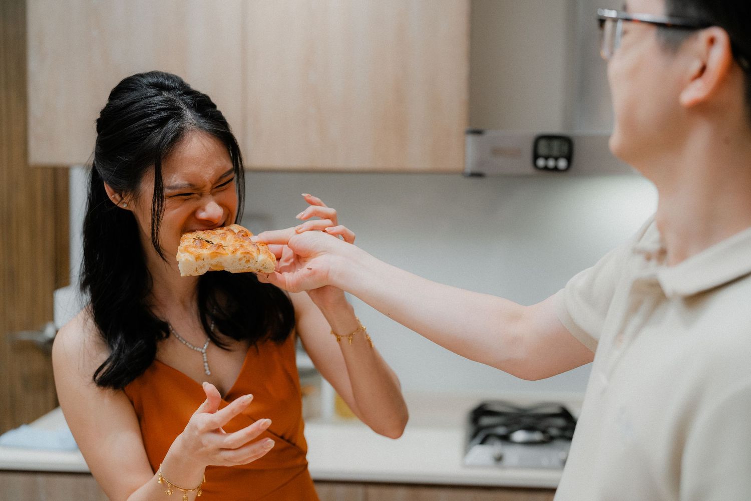 Two people sharing food together while cooking in a modern kitchen.
